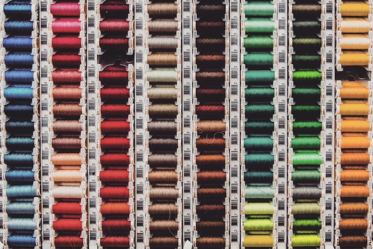 A vibrant array of colored thread spools neatly organized in rows, perfect for sewing enthusiasts.
