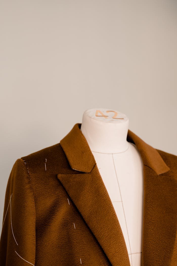 Close-up view of a brown blazer on a mannequin showcasing tailoring design and fabric.